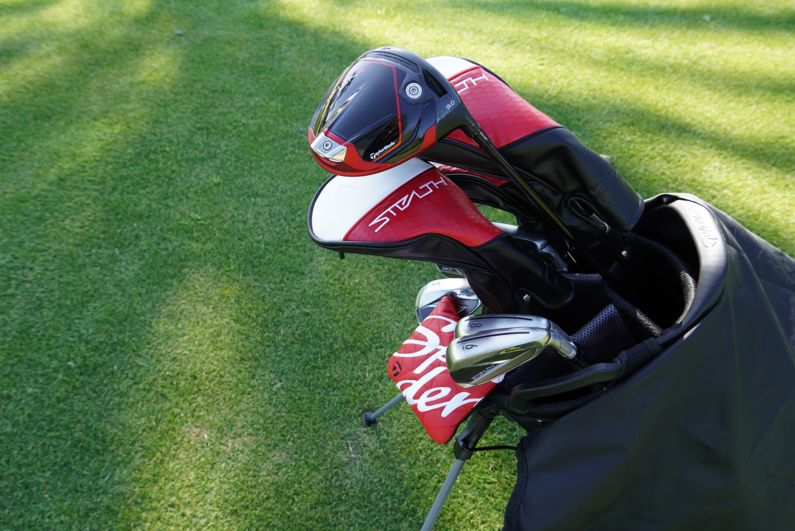 A bag of clubs with a rack of shirts in the background of a proshop 